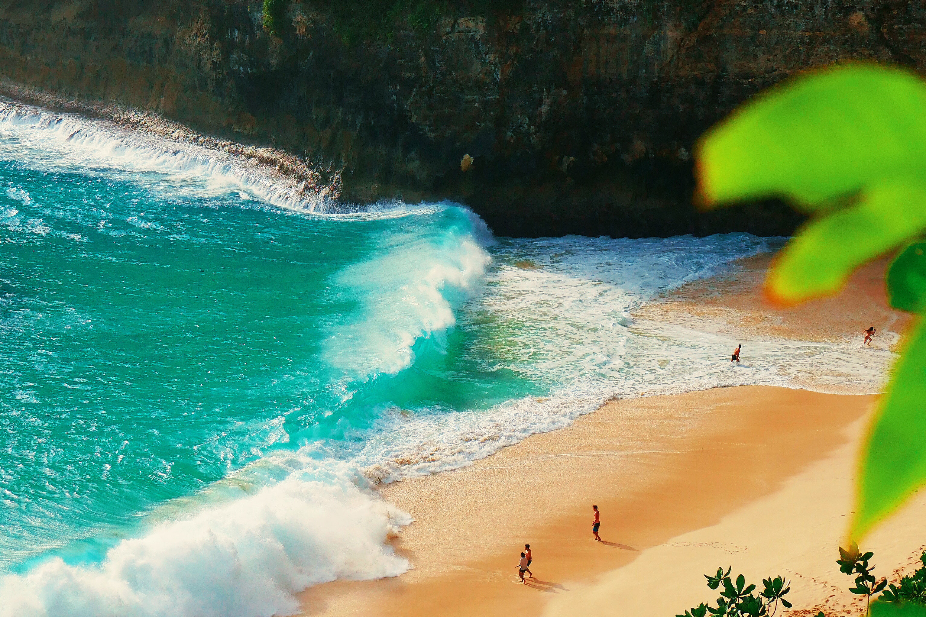 Birds eye view of a beach in Akari Bay, with large bright teal waves.