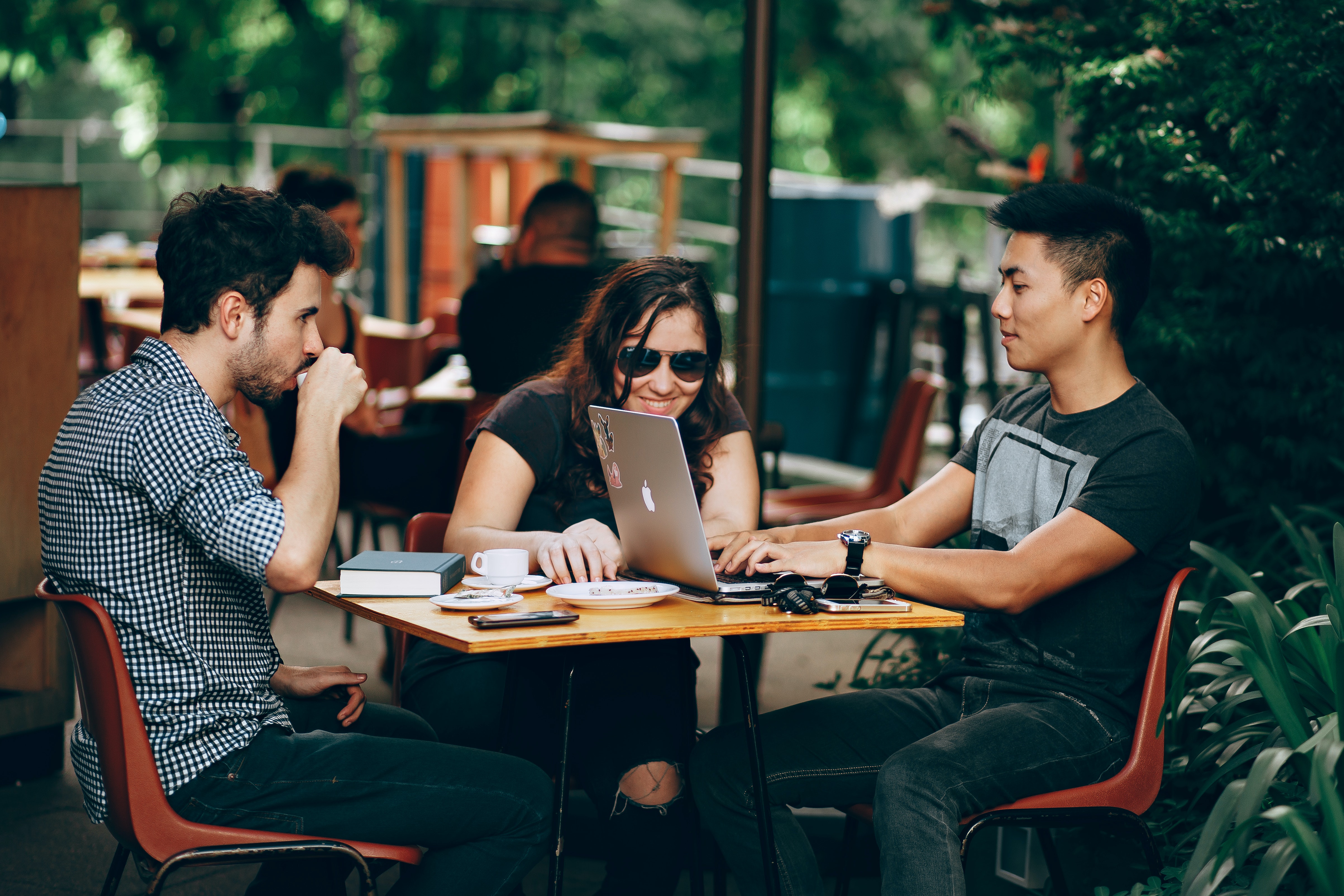 3 customers sitting at a table smiling and working.