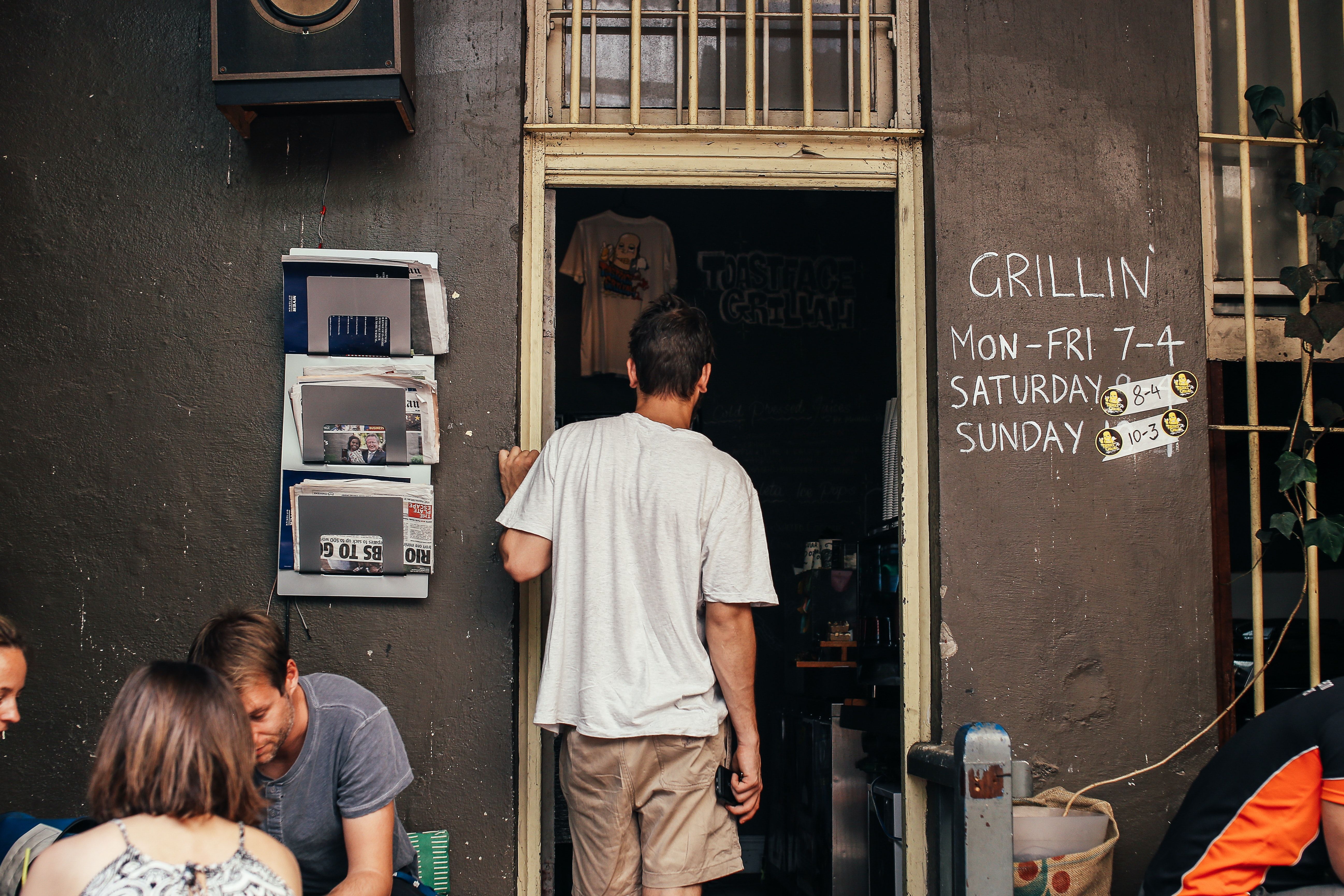 A man standing in the doorway of a coffee shop looking in.